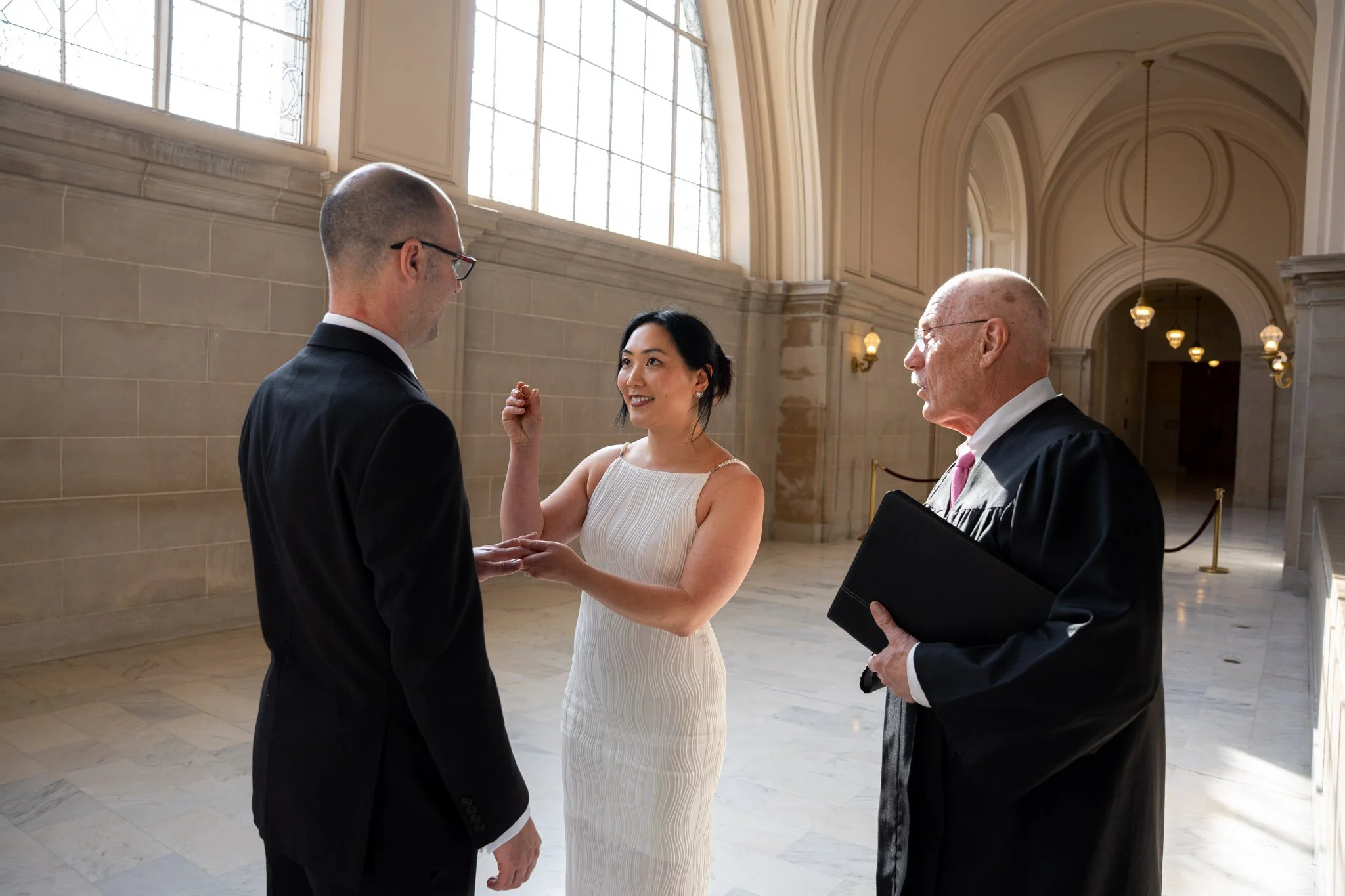 SF City Hall wedding photography — bride and groom exchanging rings inside San Francisco City Hall
