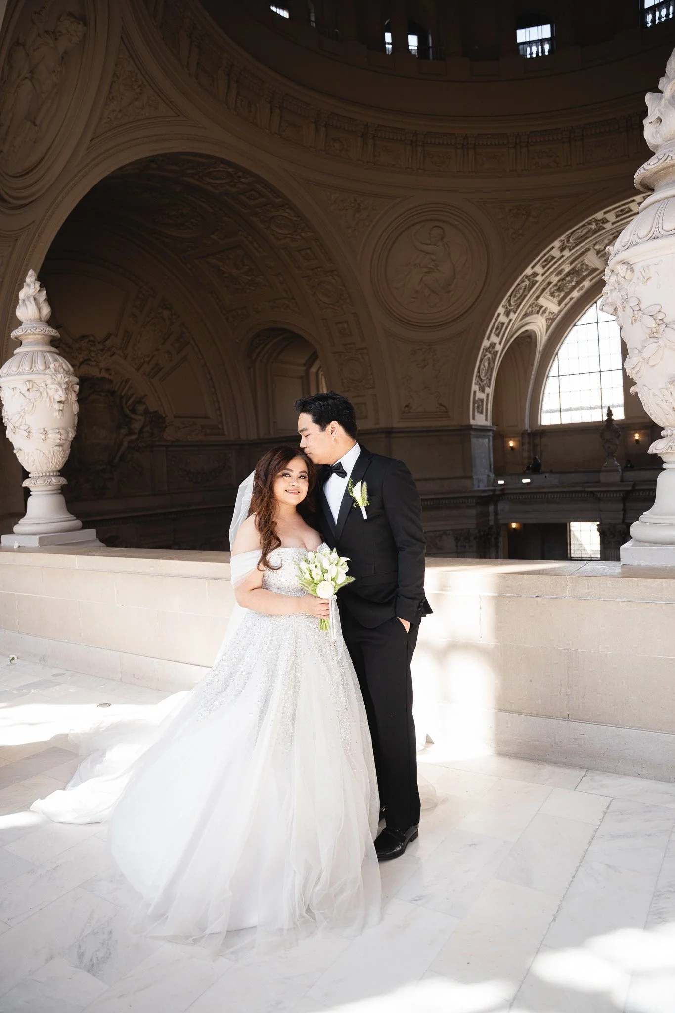 SF City Hall wedding photographer — bride and groom kissing inside San Francisco City Hall
