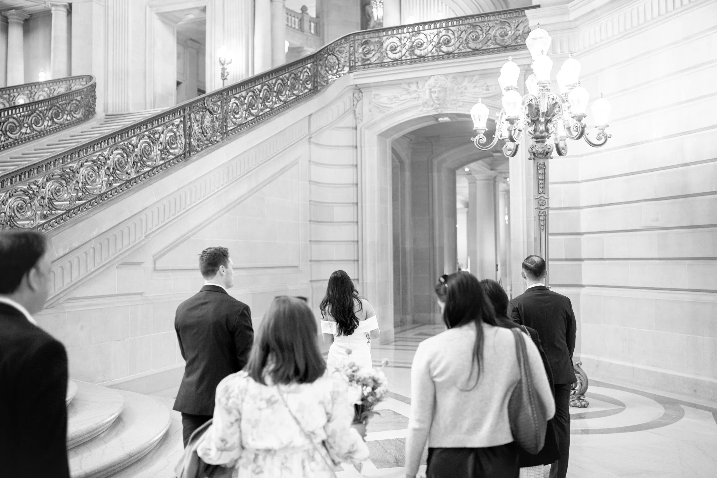 Wedding party walking down the grand staircase inside San Francisco City Hall.