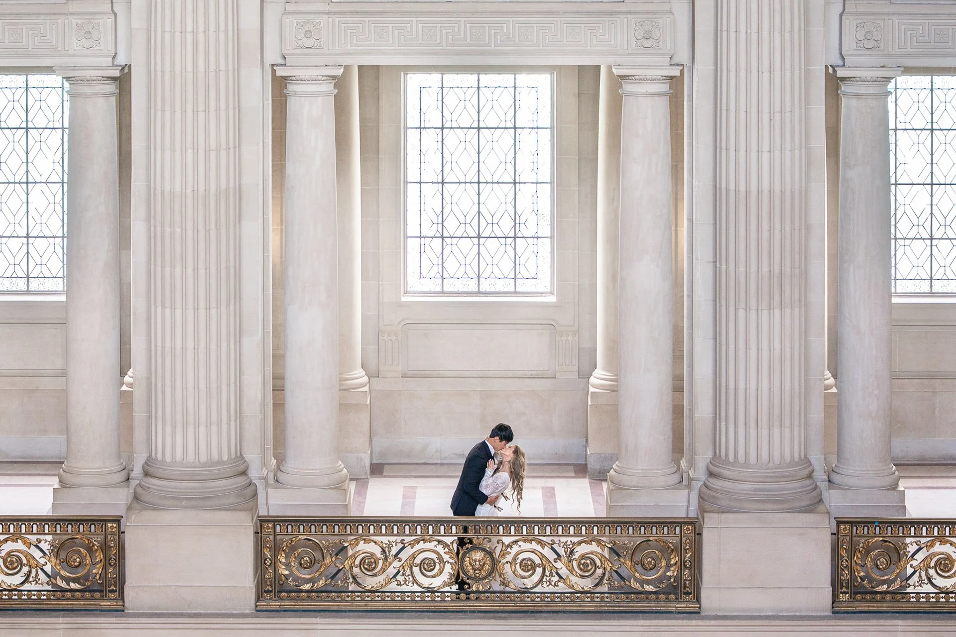 Bride and groom sharing an intimate moment on a balcony at San Francisco City Hall.