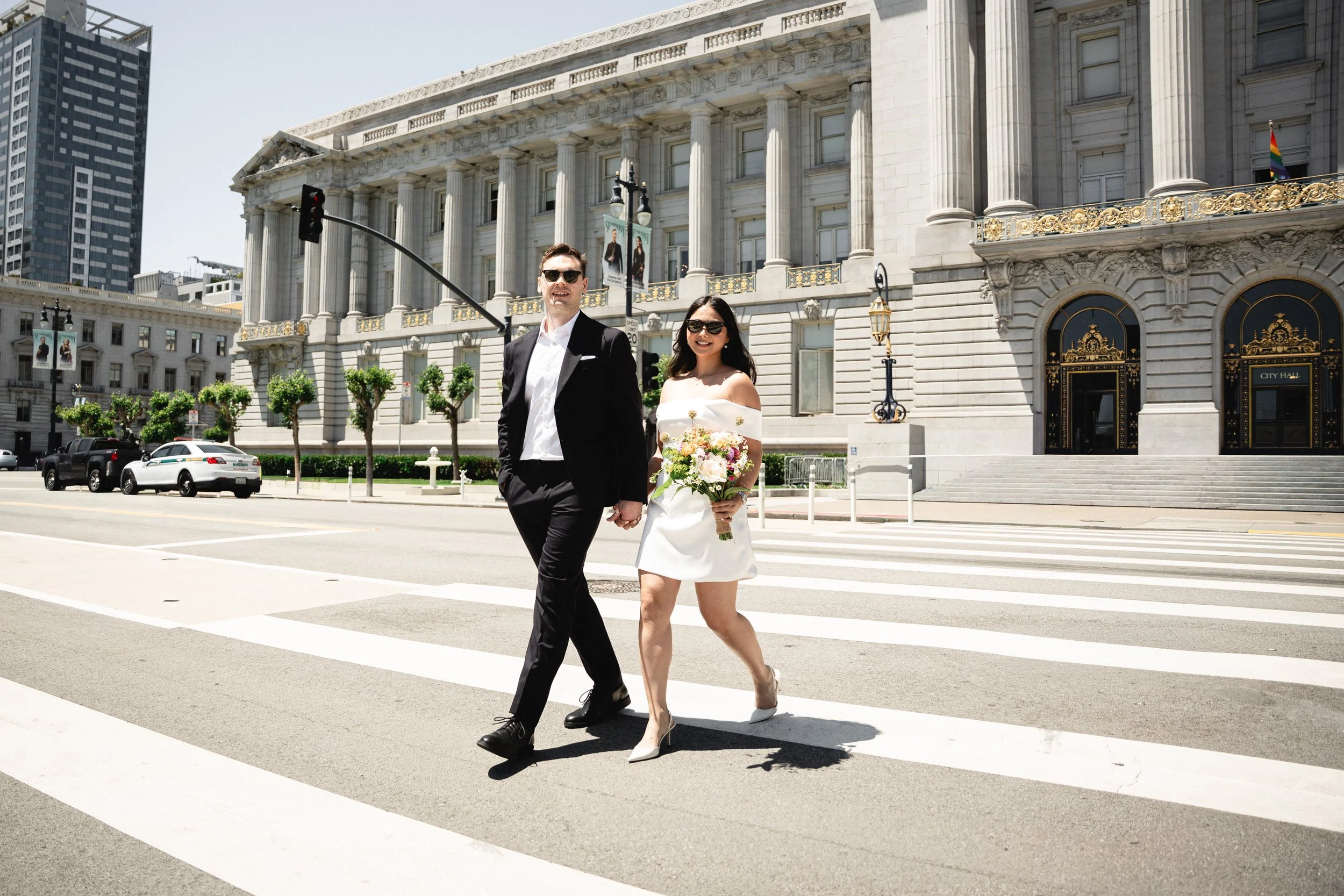 Bride and groom crossing the street in front of San Francisco City Hall.
