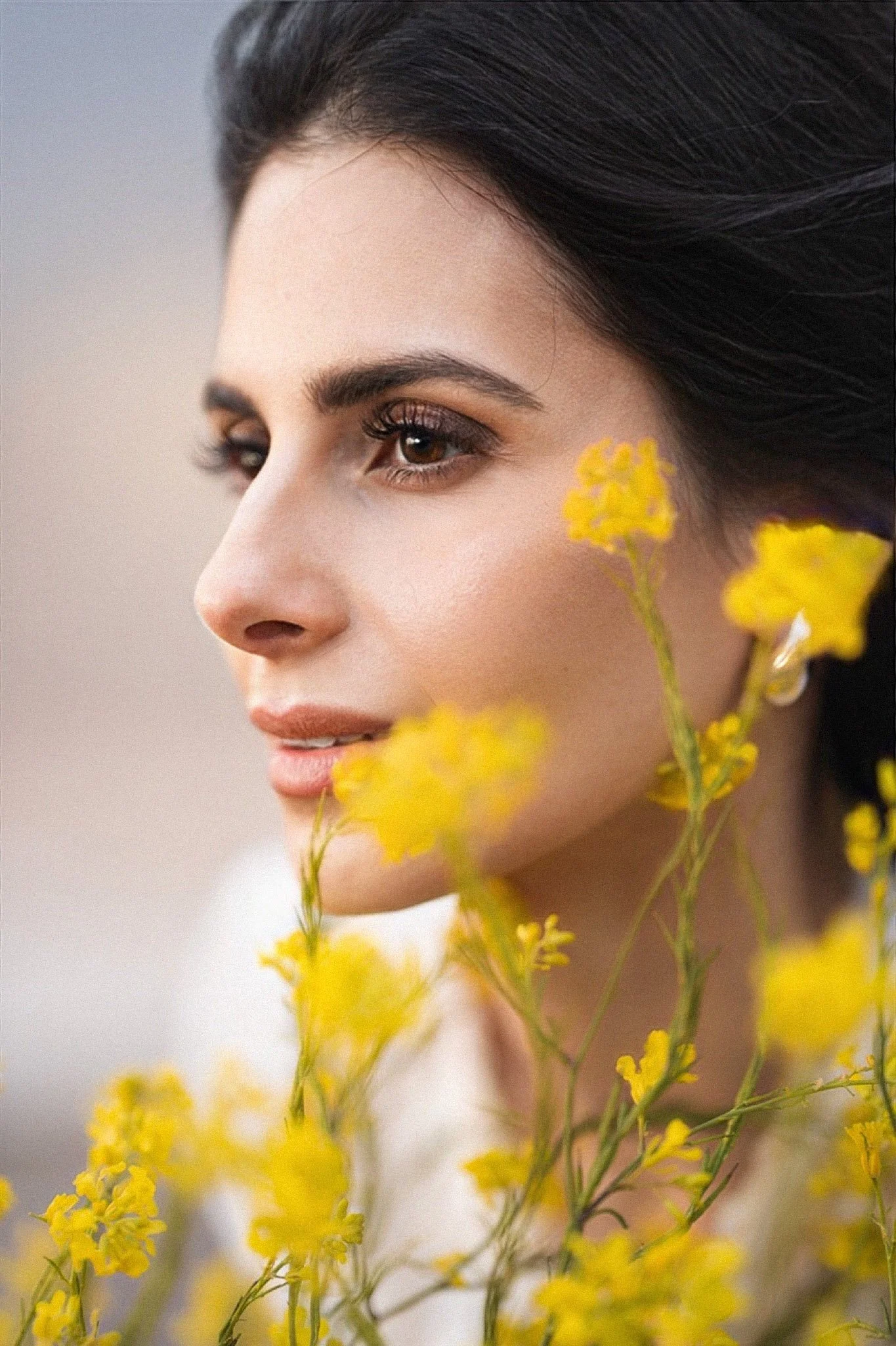 Close-up bridal portrait with dark hair and soft makeup among yellow wildflowers in Marina Alviso near San Jose.