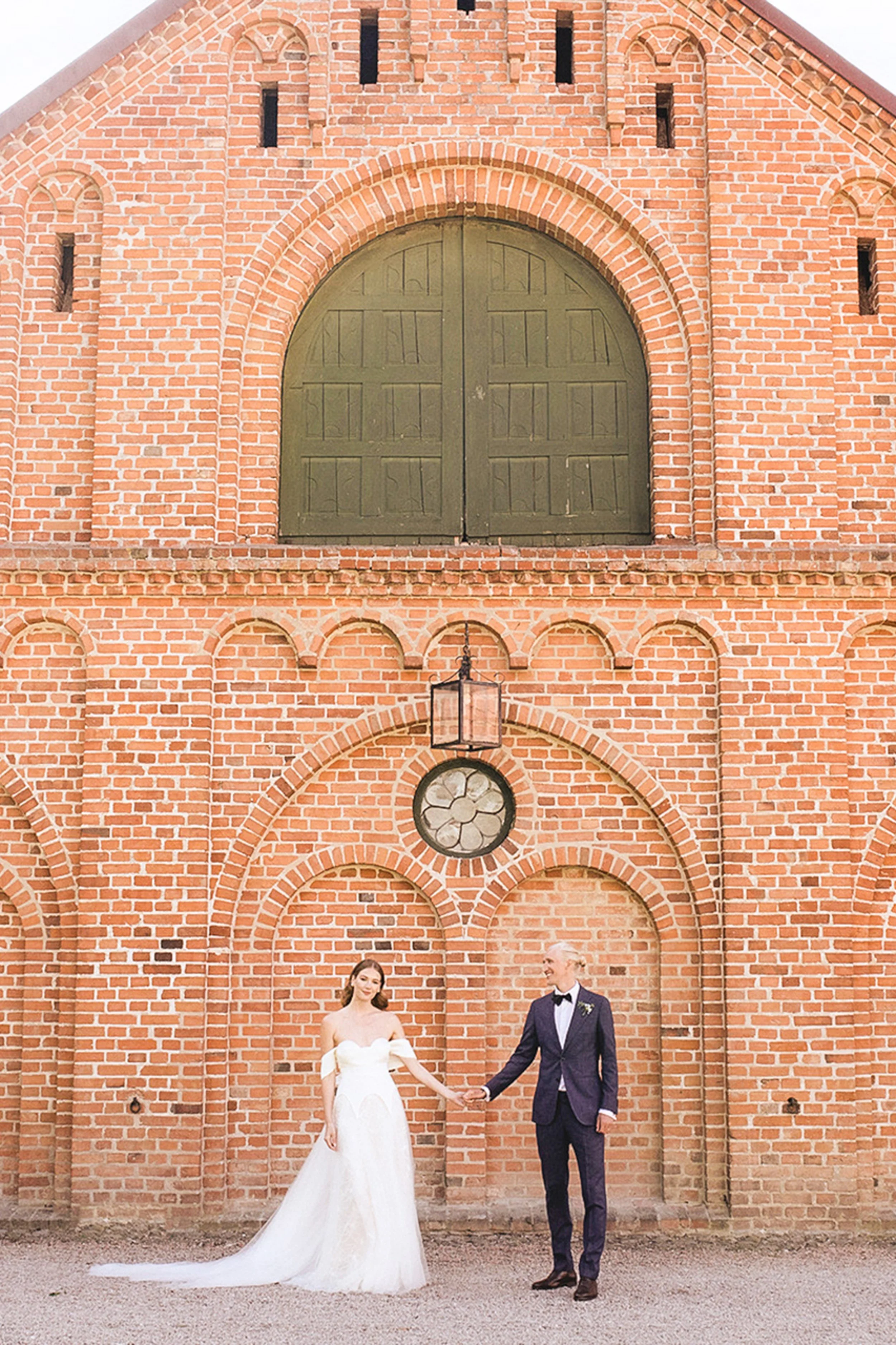 Bride and groom holding hands outside a church.