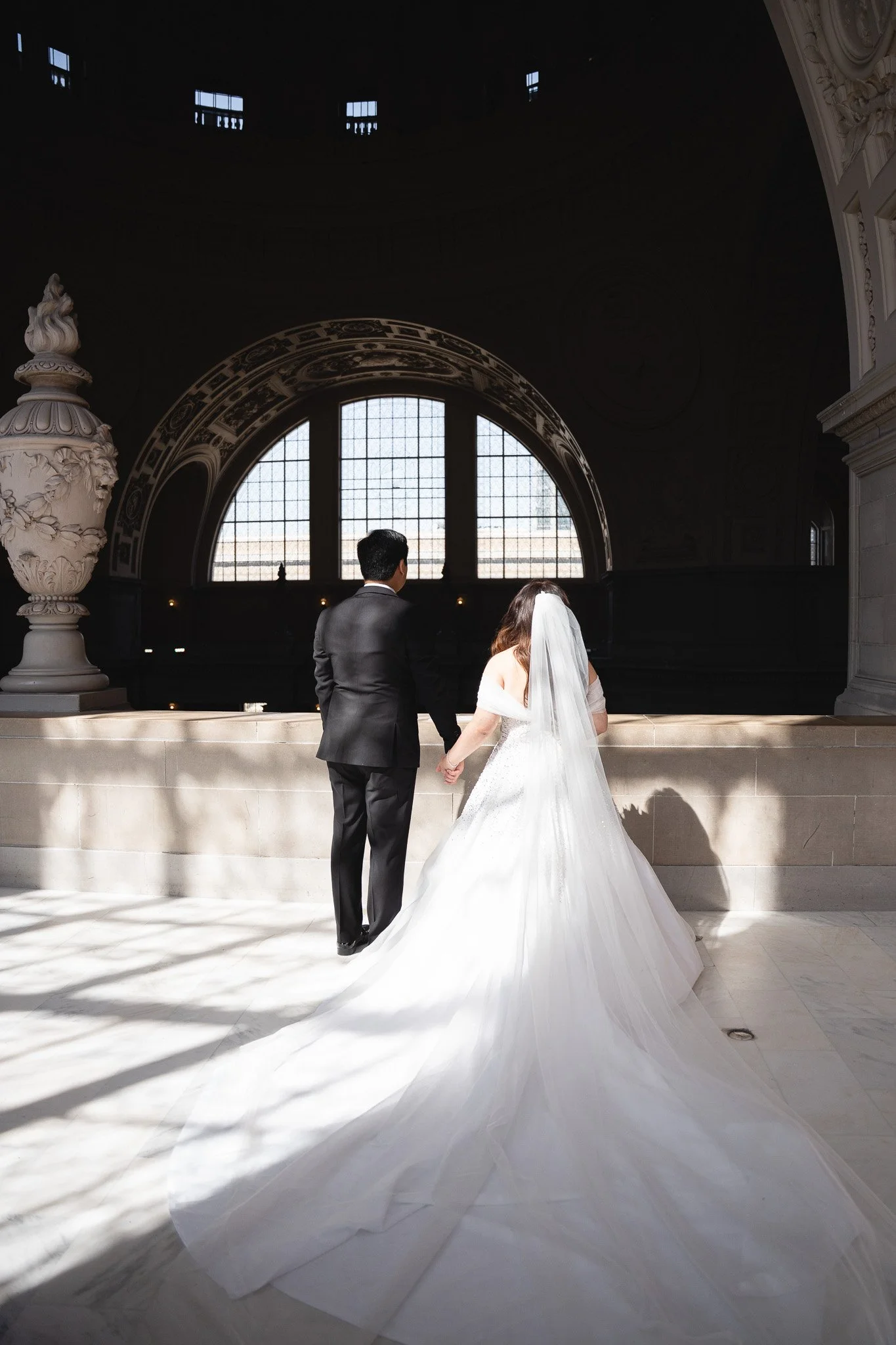 A bride and groom holding hands inside SF City Hall 1 Dr Carlton B Goodlett Pl, San Francisco, CA 94102.