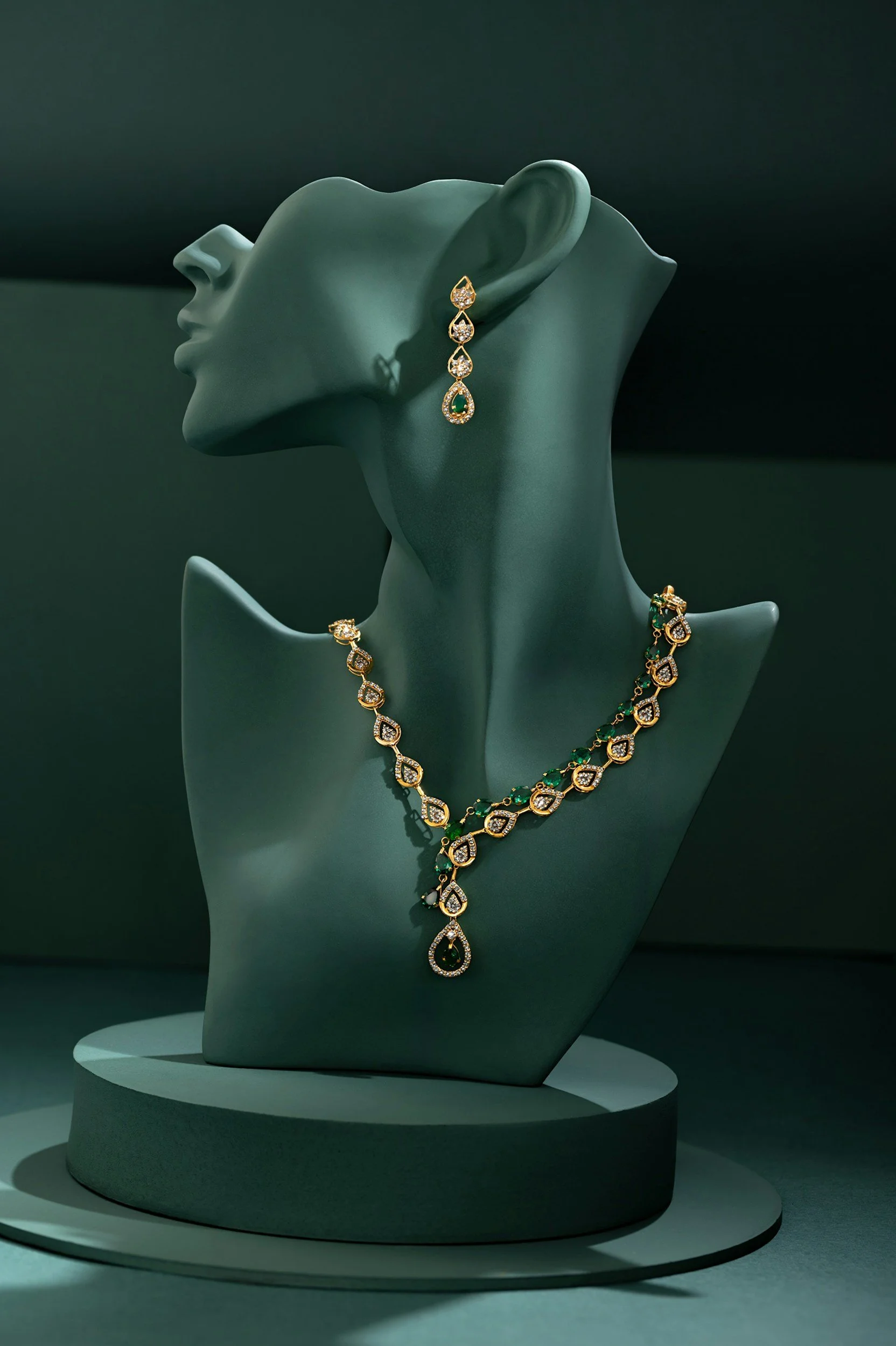 Collier, boucles d'oreilles et pendentif en or et diamants sur une statue en vert