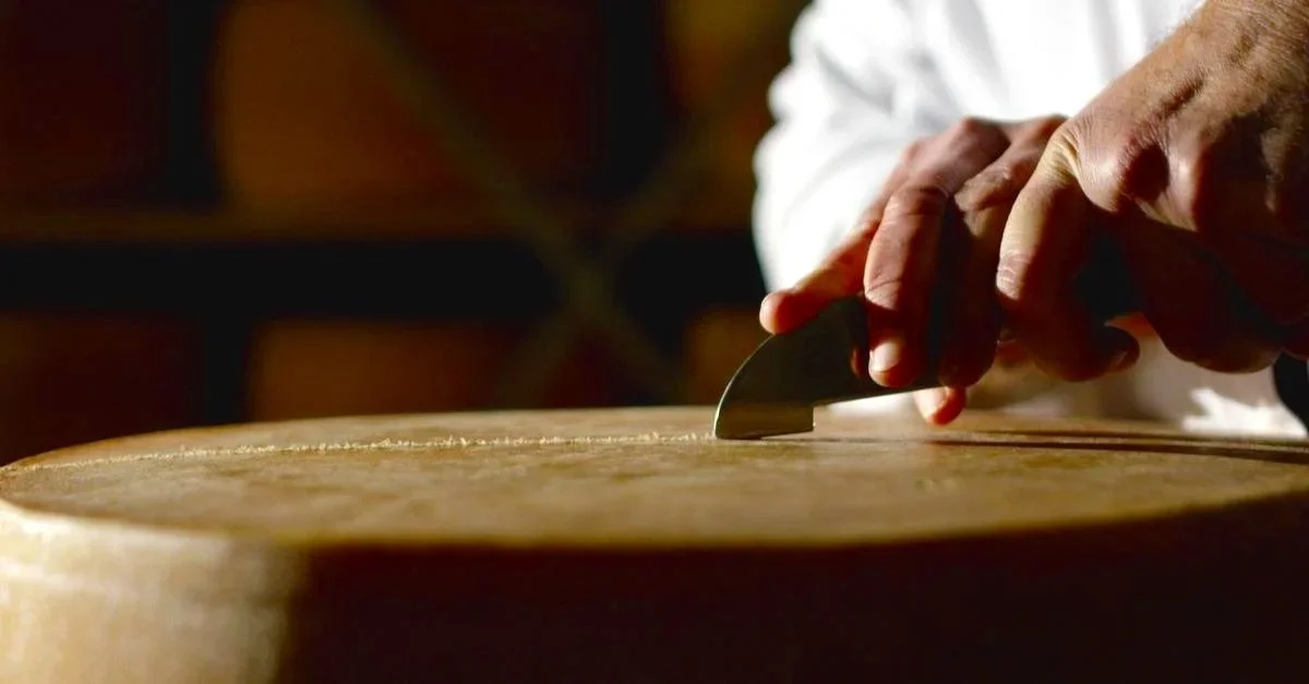 A person cutting a wooden board with a utility knife.
