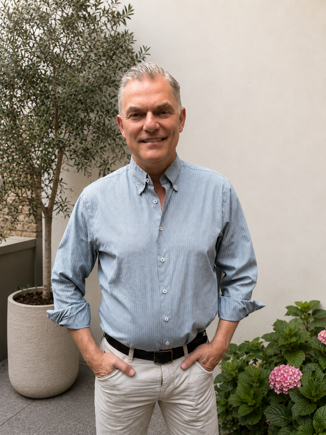 Jakob Holm standing in a garden surrounded by plants and flowers.