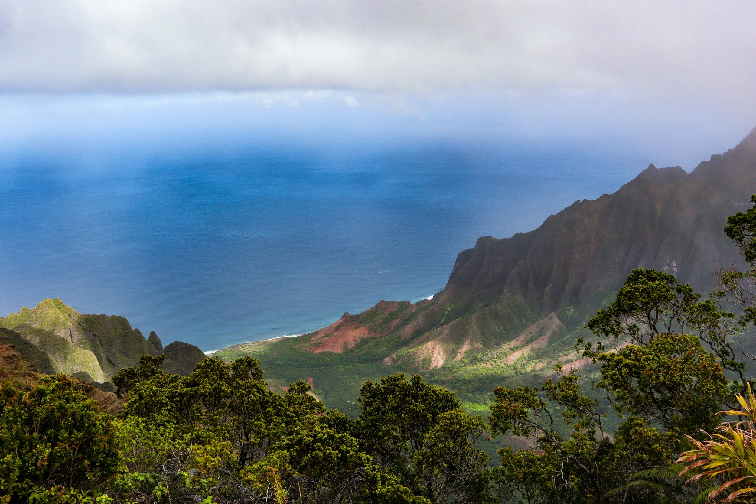 Lush Hawaiian coastline with dramatic green mountains and views of the Pacific Ocean.