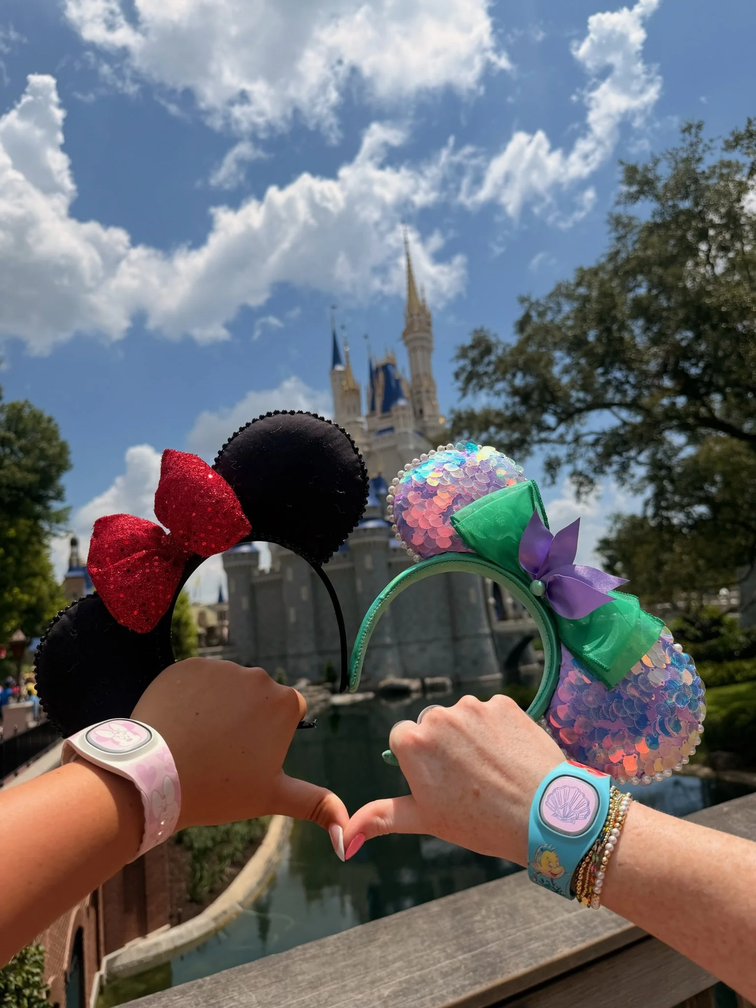 Travelers making a heart with their hands in front of Cinderella Castle at Walt Disney World.