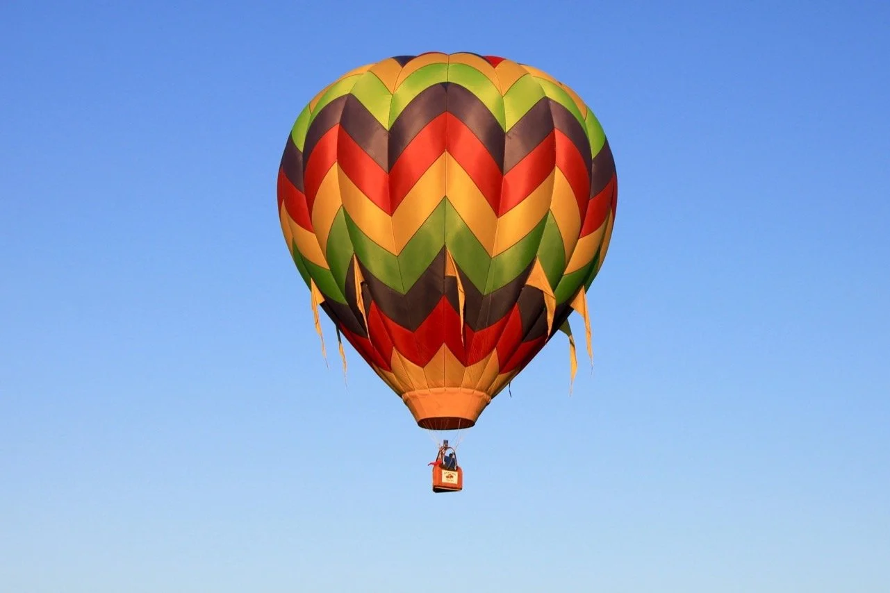 Colorful hot air balloon floating in clear blue sky flying over St. Helena