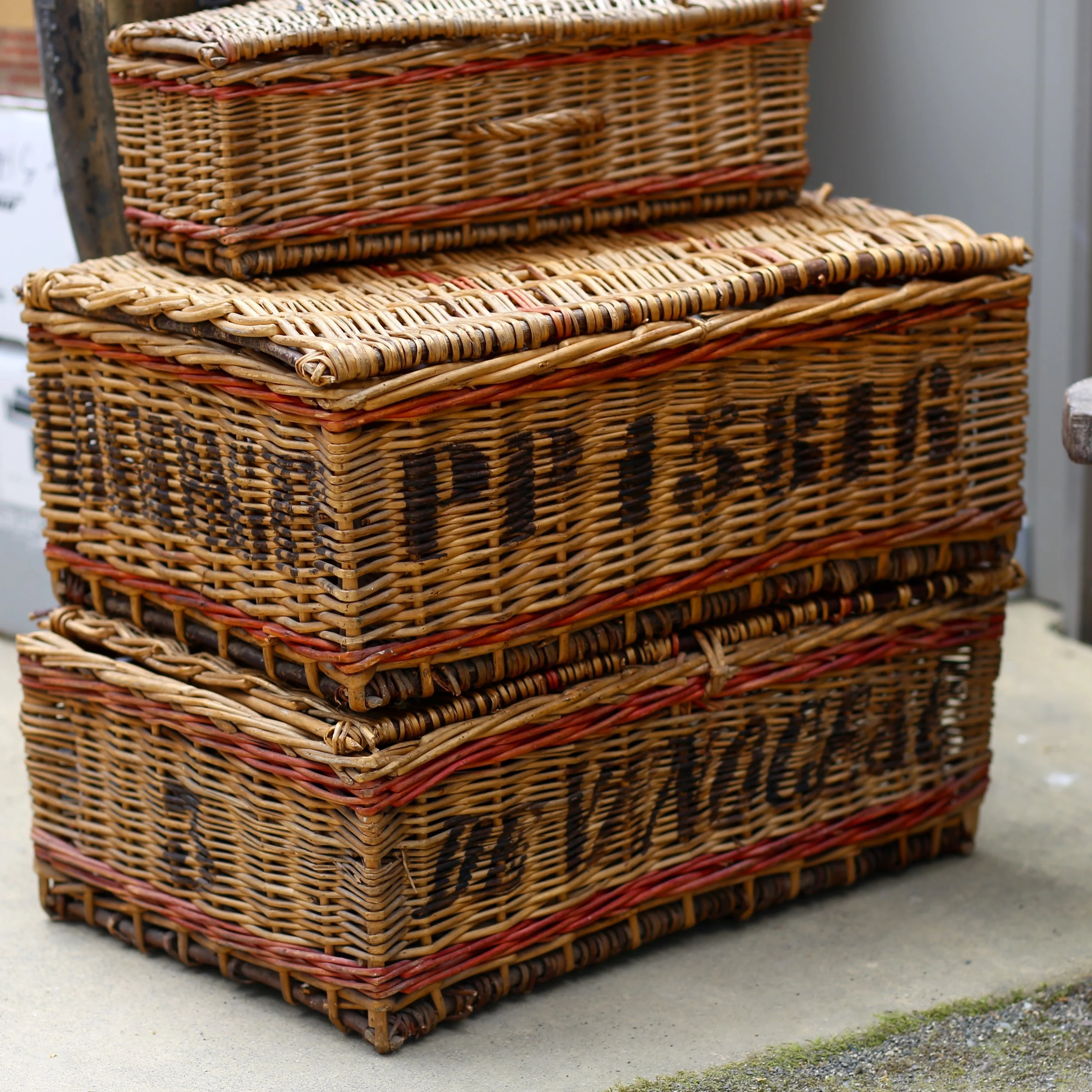 Stacked woven wicker baskets outdoors on a concrete surface.