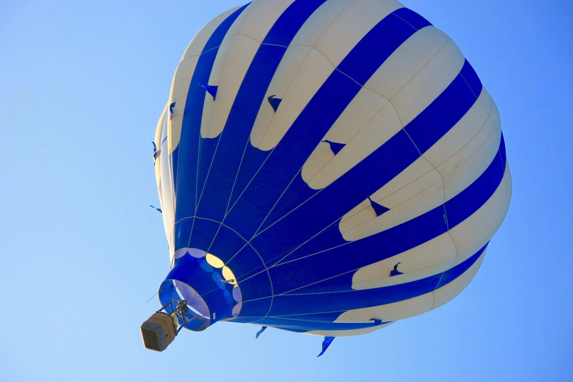 A hot air balloon with a blue and white striped pattern floating in the sky flying over the Napa Valley