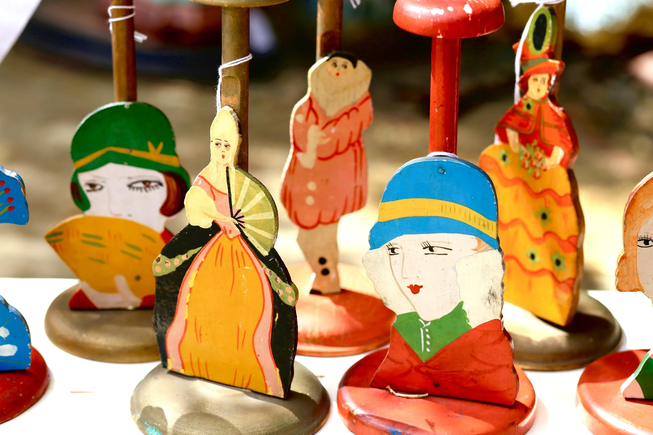 Colorful wooden figurines depicting characters in traditional clothing, arranged on circular stands.