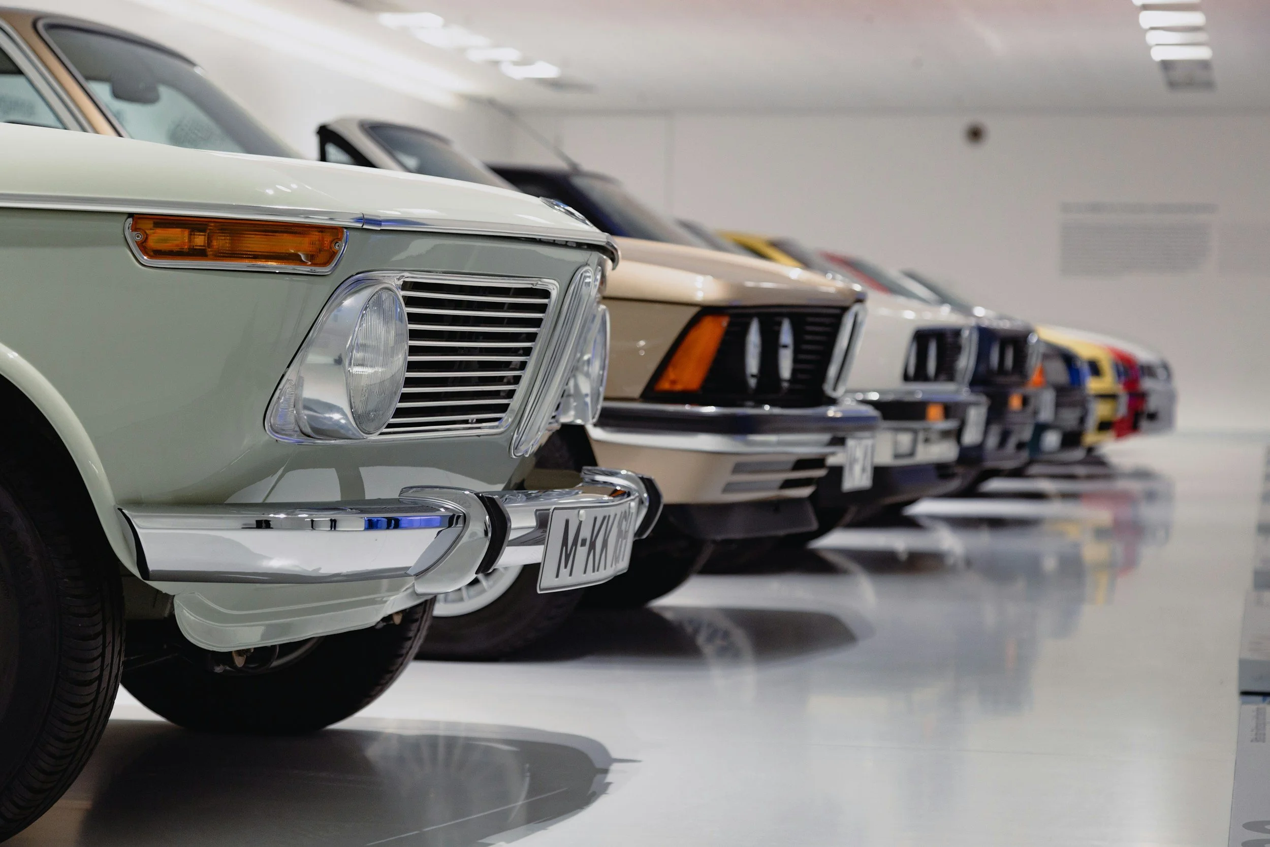 Multiple vintage cars parked in a row in an indoor garage or showroom.