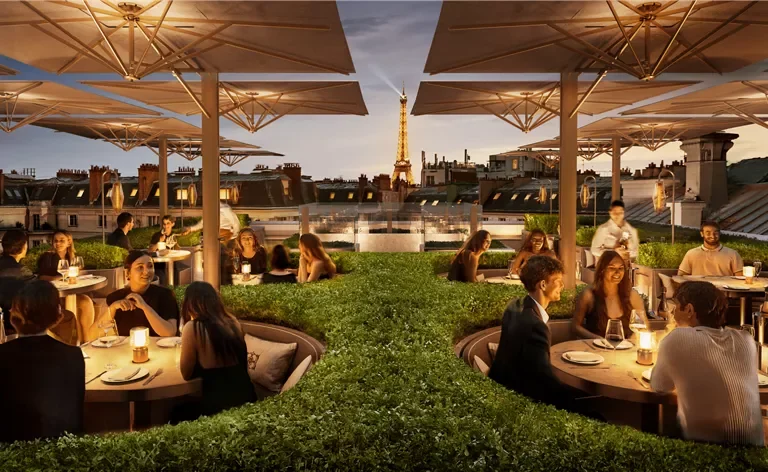 People dining at outdoor rooftop restaurant in Paris with the Eiffel Tower in the background during evening.