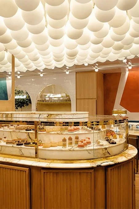 Decorative display case filled with assorted baked goods in a stylish bakery or cafe with unique ceiling decor.