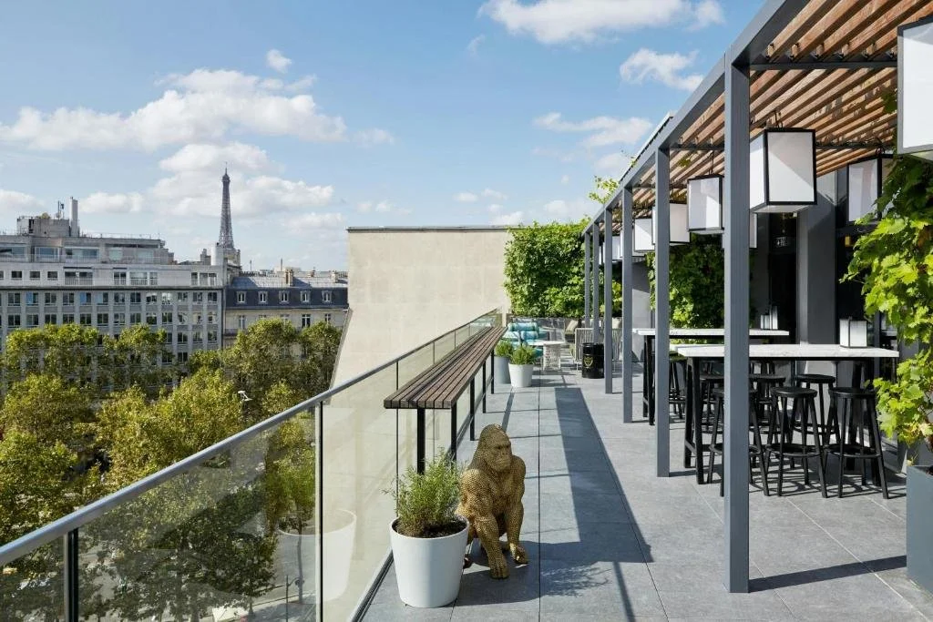 Rooftop terrace with seating, plants, and a view of Paris, including the Eiffel Tower in the background.