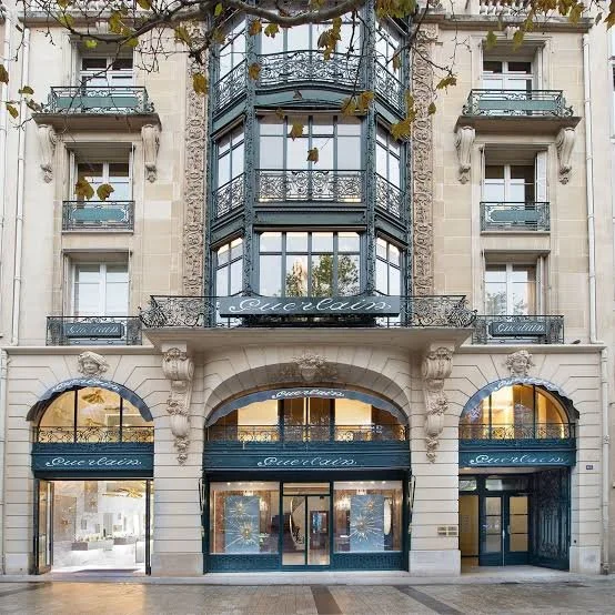 Exterior of a multi-story building with a hotel named 'Louvre' and retail storefronts at the ground level.