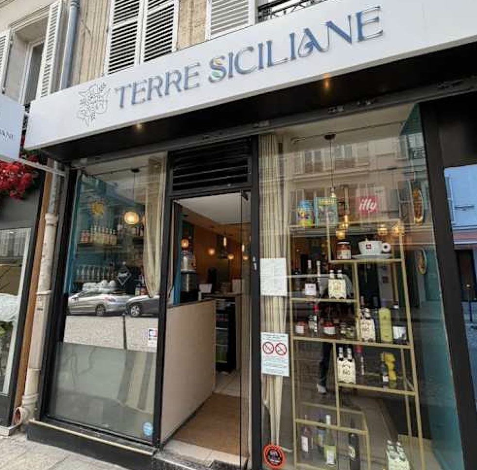 The exterior of a store named Terra Siciliane with glass doors and shelves displaying various products inside.