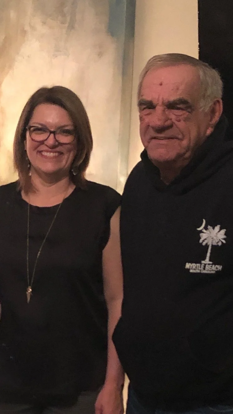Belinda standing beside her father, both smiling at the camera.