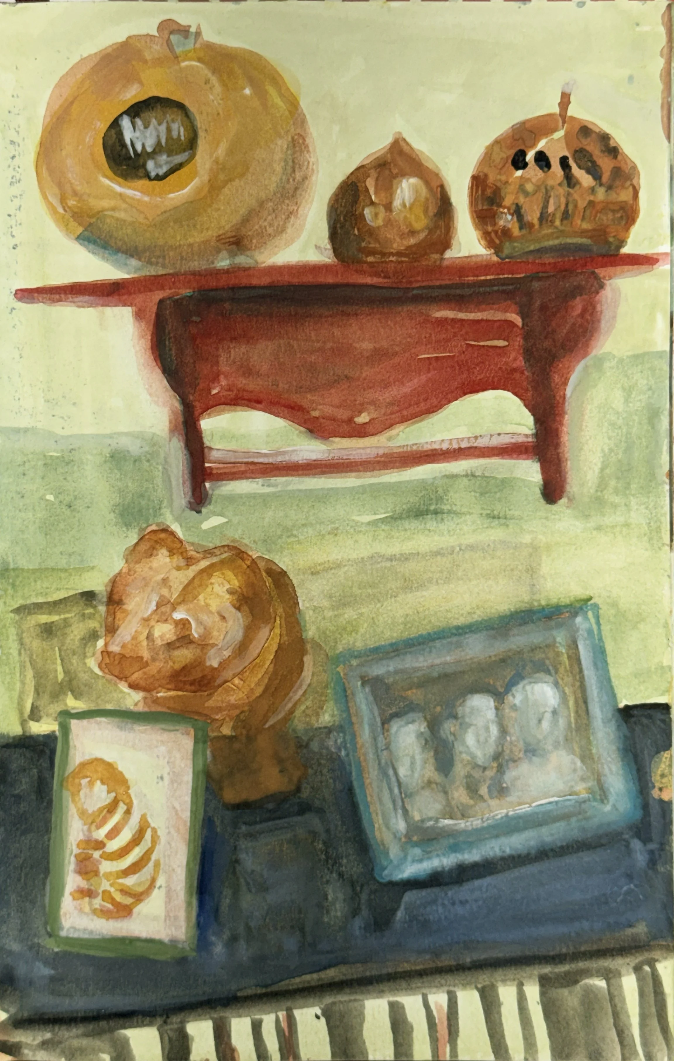 Watercolor painting of a still life scene with pumpkins on a red wooden table, a framed photo, and a small picture of a pumpkin with bones.