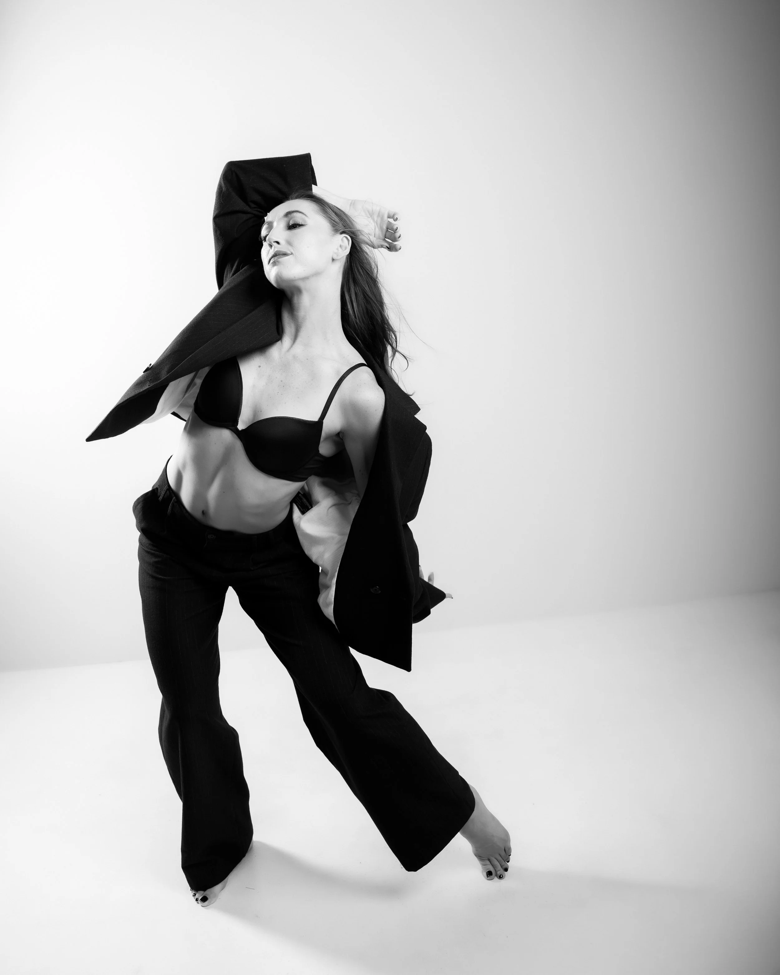 Skylar Schultz creating an expressive contemporary dance shape in a black suit.