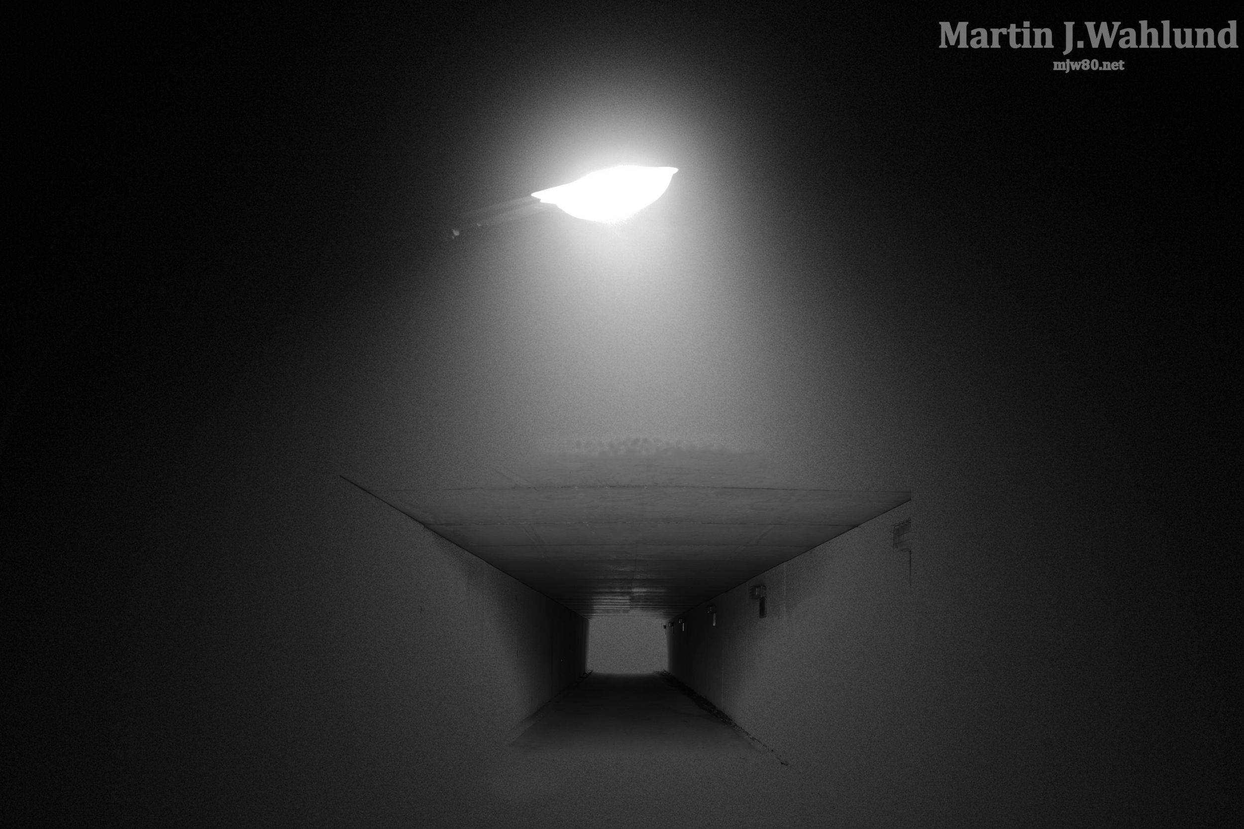 A dark hallway with a bright light at the end, creating a contrast and a sense of depth.