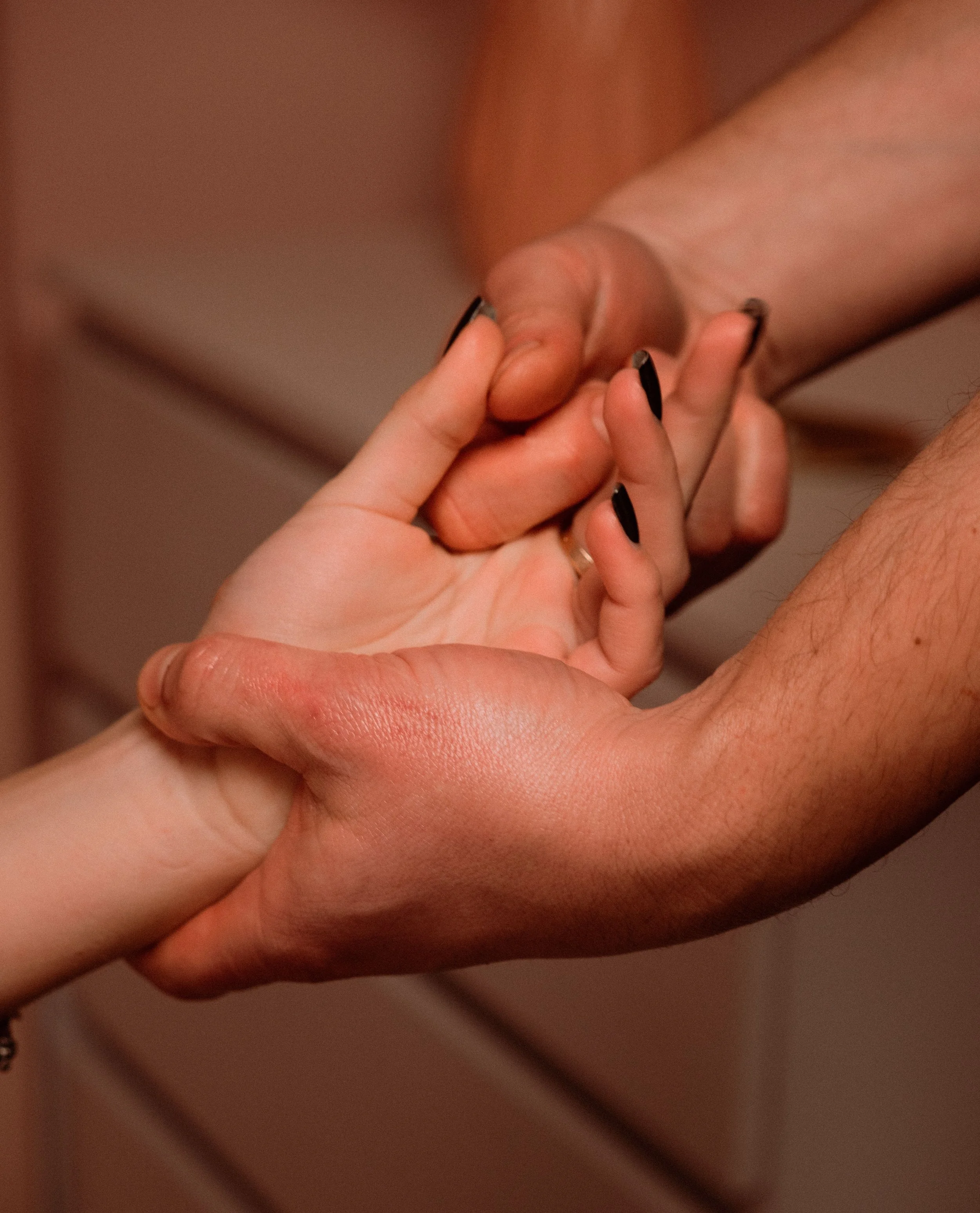 Close-up of a person holding another person's hand, with the focus on their fingers and nails.