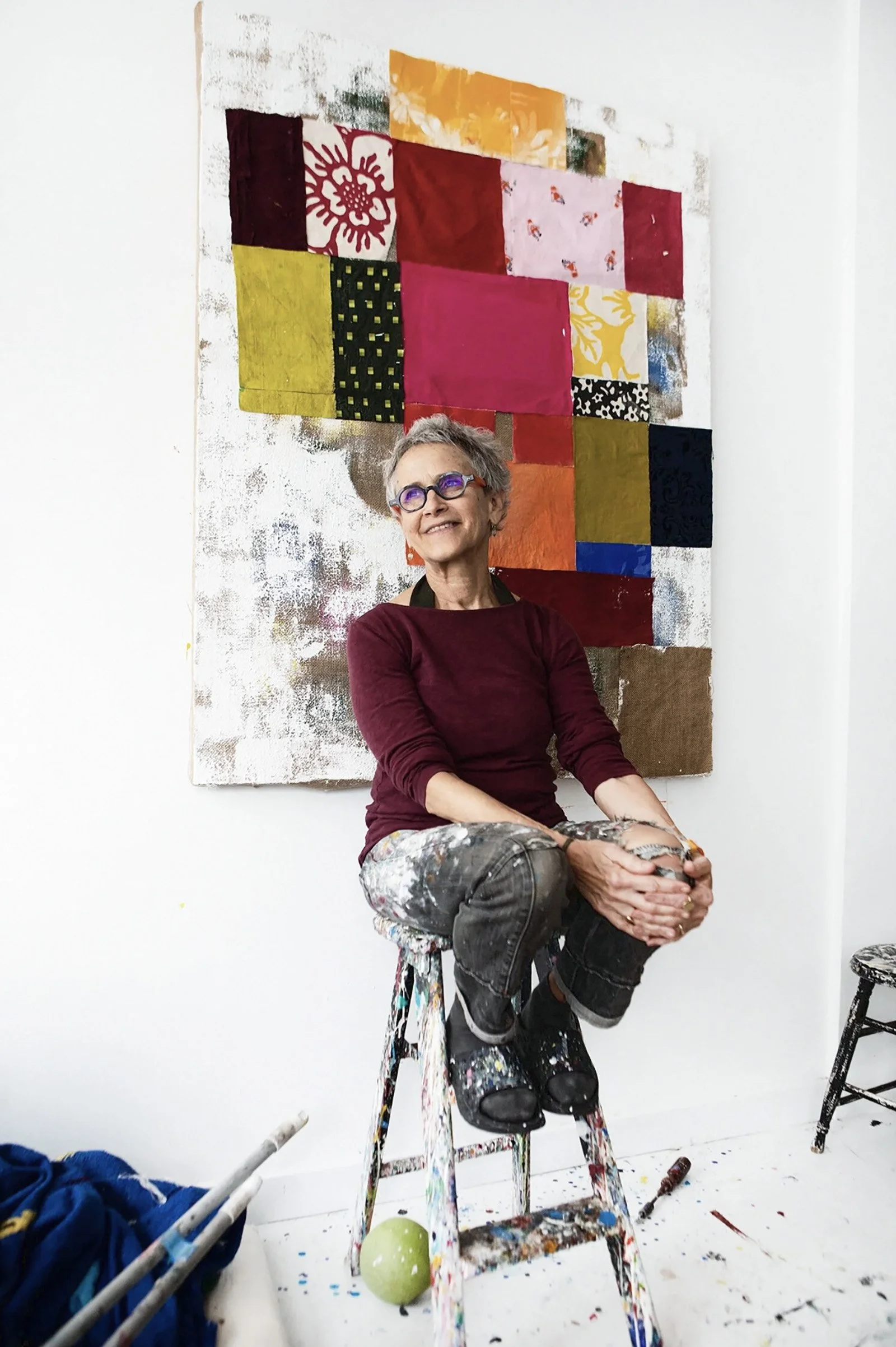 Jessica Weiss_Artist sitting on wooden stool in from of her art work