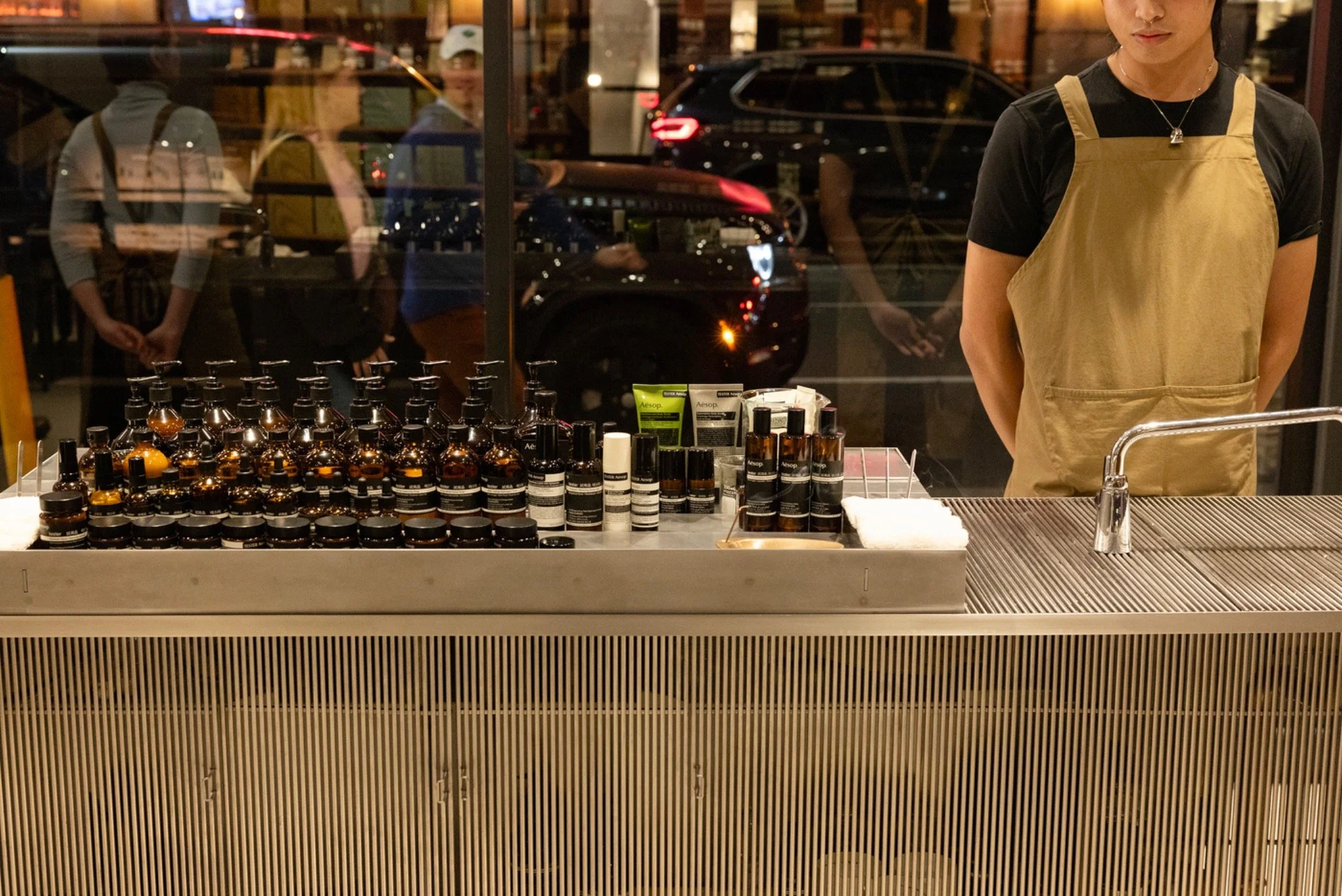 An Aesop staff member standing behind a display of skincare products inside the NoMad store.