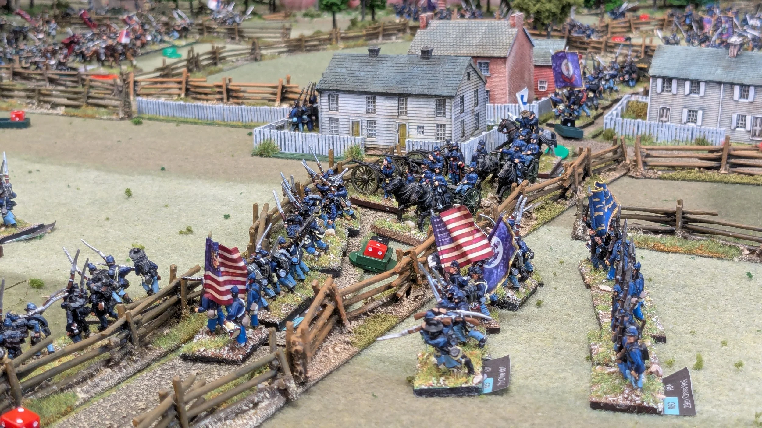 Miniature battlefield scene with toy soldiers, flags, and buildings, depicting a historical military conflict.