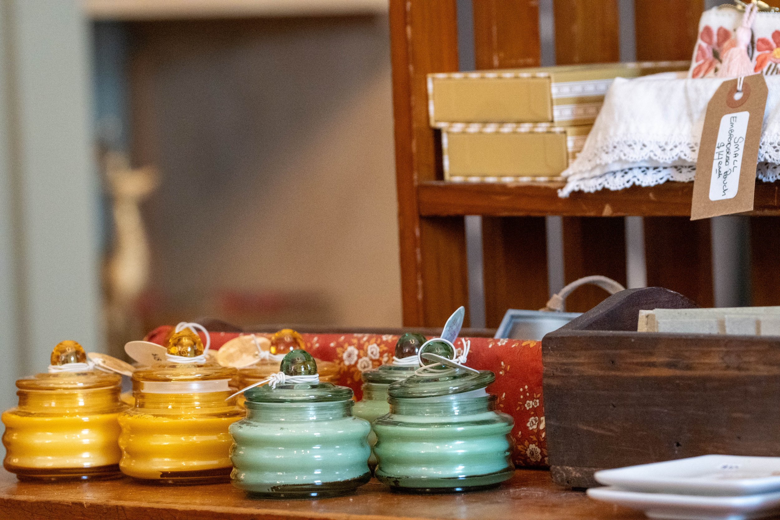 Colorful ceramic jars with lids displayed on a wooden table at a market or shop.