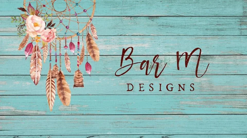A turquoise wooden background with a pink and brown dreamcatcher on the left and the words 'Bar M Designs' written in brown and red in the center.