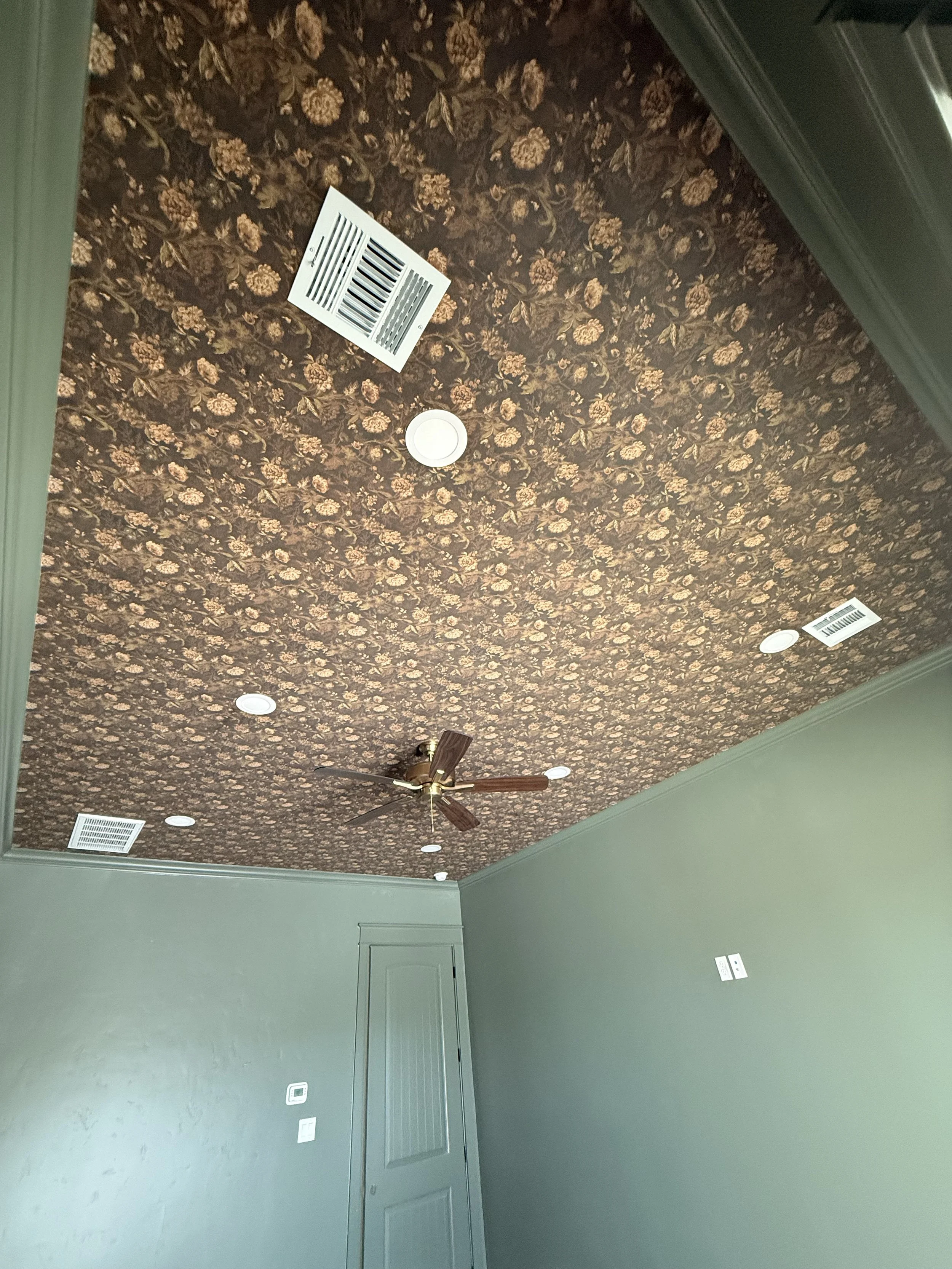 Ceiling with floral patterned wallpaper, vent, recessed lights, a ceiling fan, and a green wall with a door.