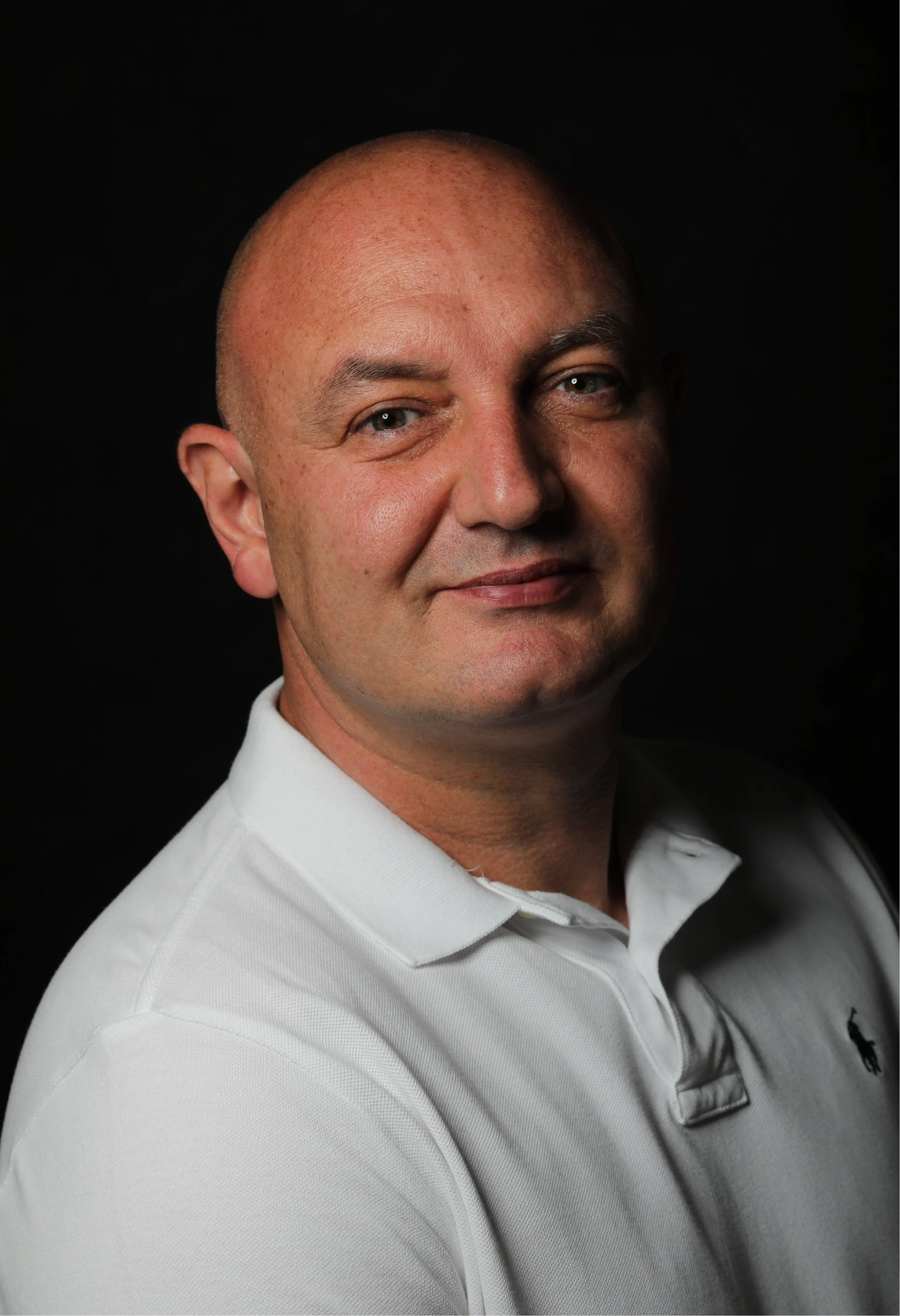 Close-up portrait of Garreth Quinn wearing a white dress shirt against a black background.