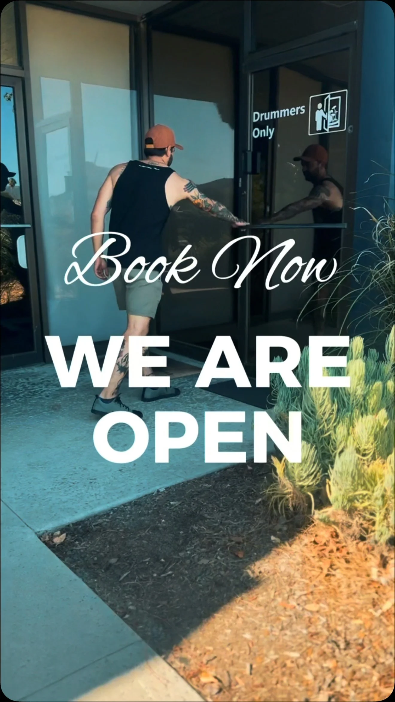 A man with tattoos and a baseball cap opening a glass door labeled 'Drummers Only.' The text 'Book Now WE ARE OPEN' is overlaid on the image.