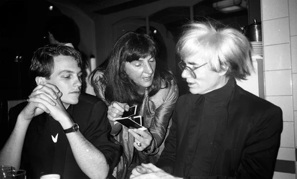New York City Ballet dancer Ulrik Trojaborg, artist:critic Edit DeAk, and art luminary Andy Warhol discussing Polaroids at The Odeon, 1986..jpg