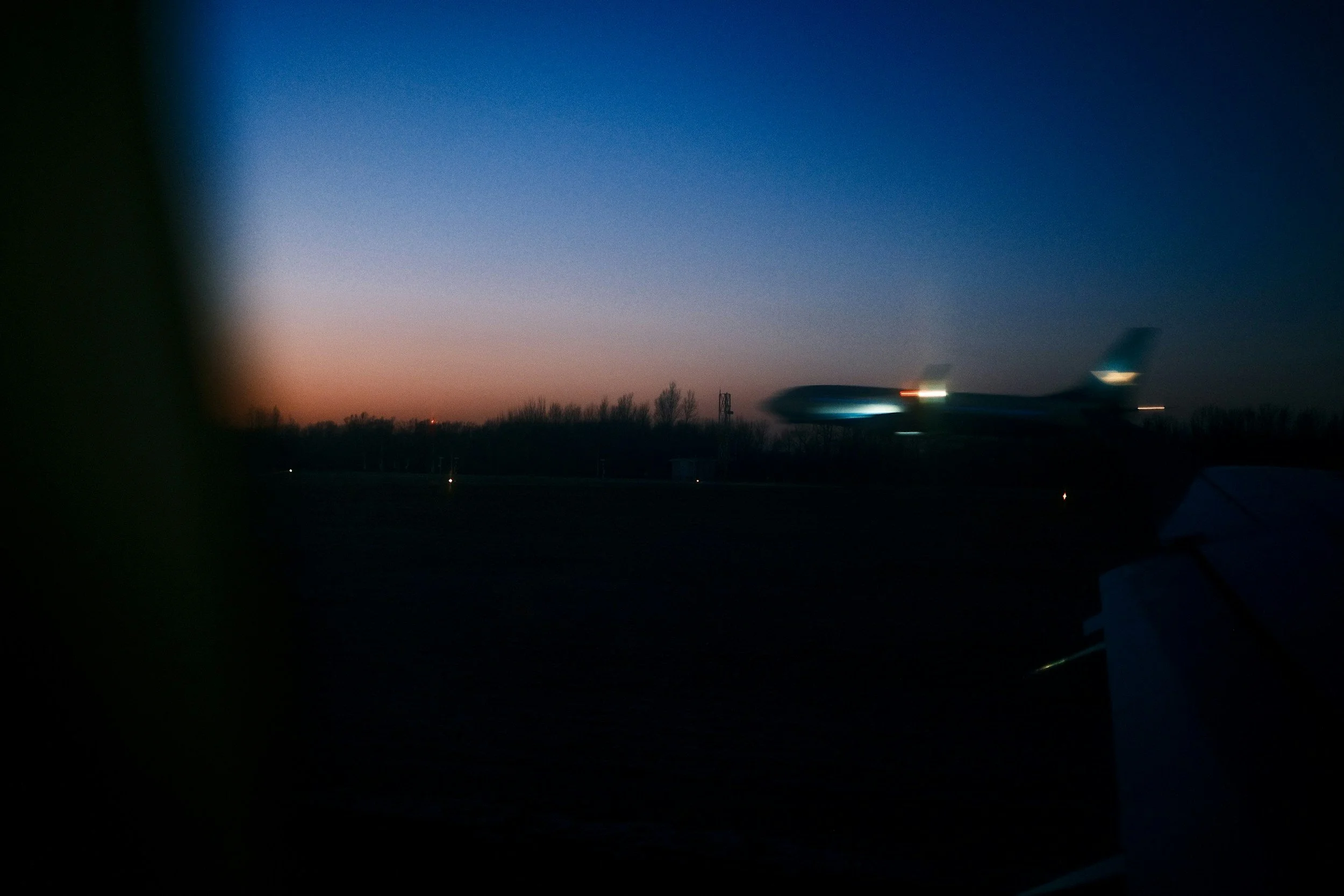 An airplane taking off during dusk with the sky transitioning from orange to deep blue.