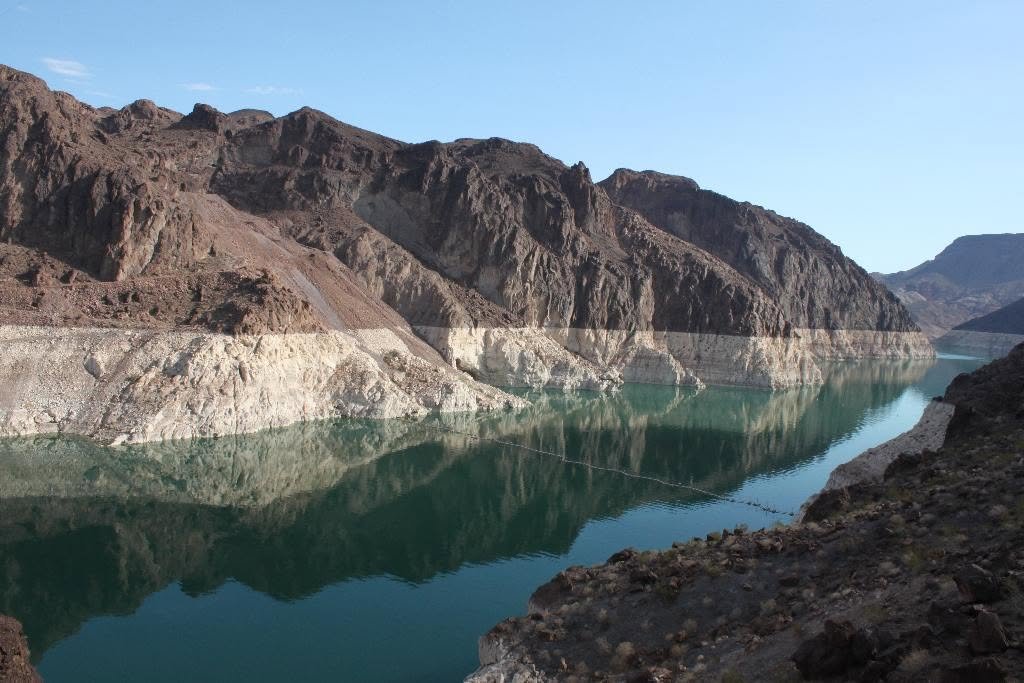 A reservoir surrounded by rugged mountains with clear, greenish water reflecting the rocky cliffs.