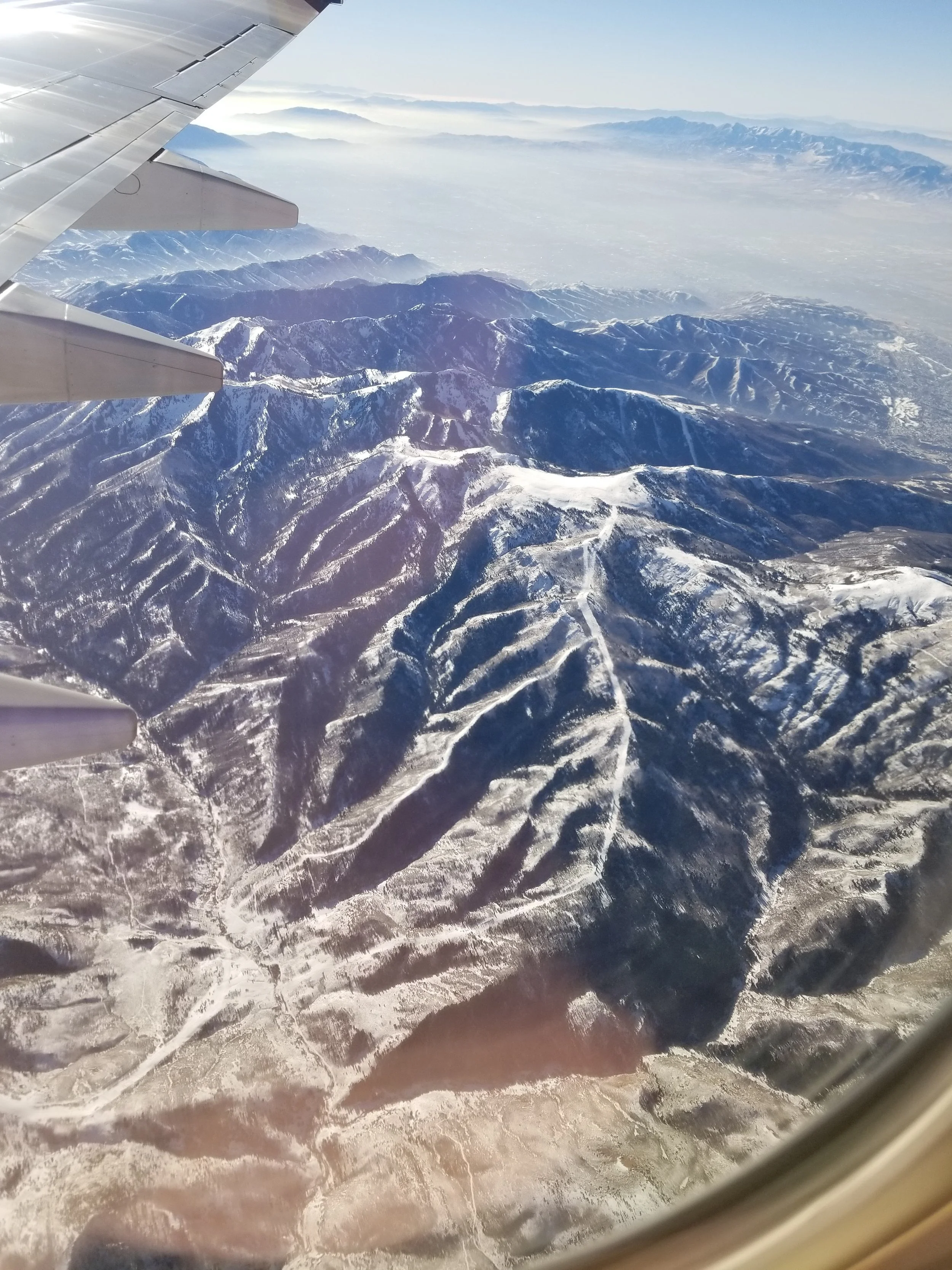 Aerial view of snow-covered mountain ranges seen from an airplane window.