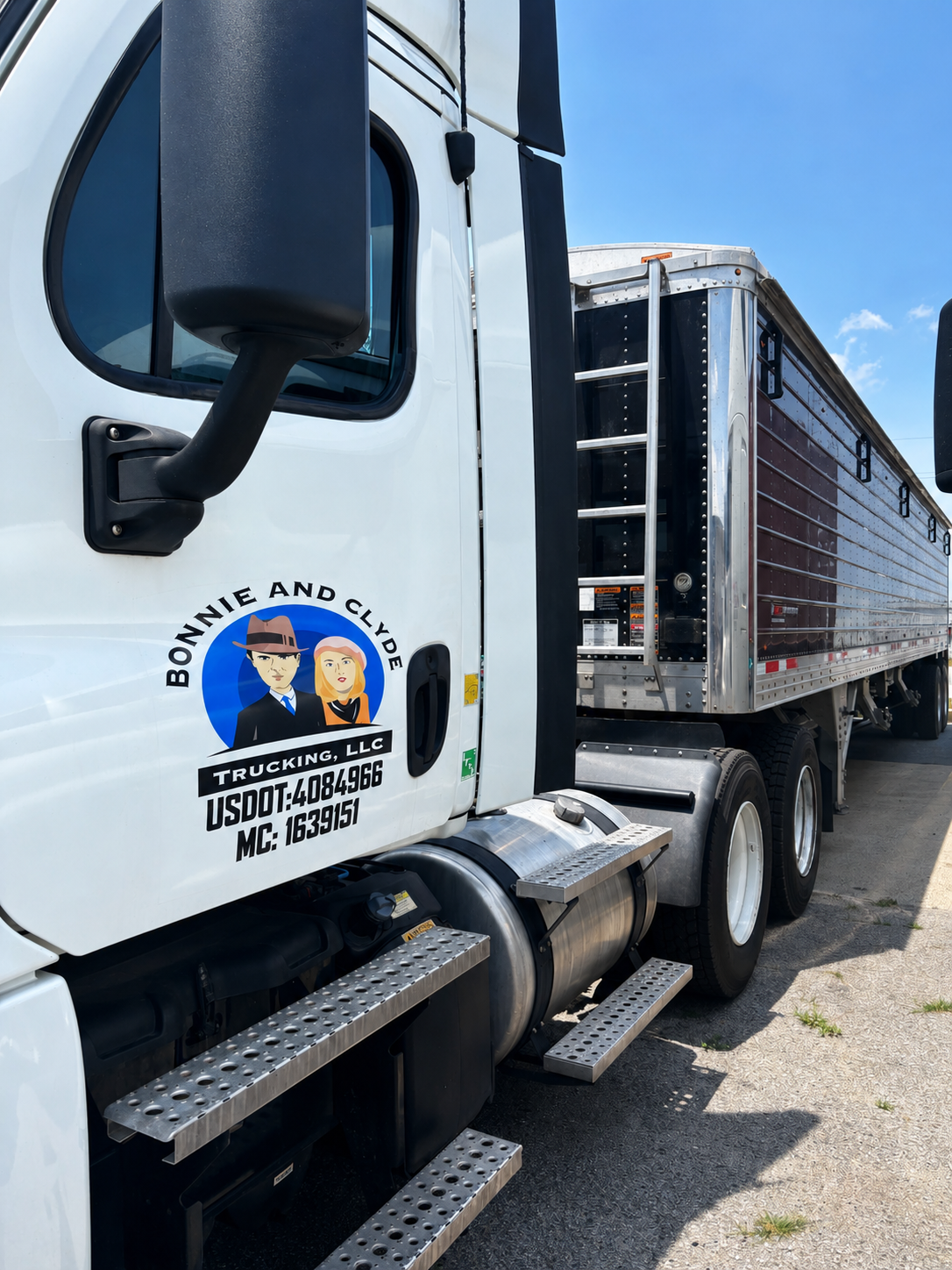 White semi-truck with a logo of Bonnie and Clyde on the door, parked outdoors under a blue sky.