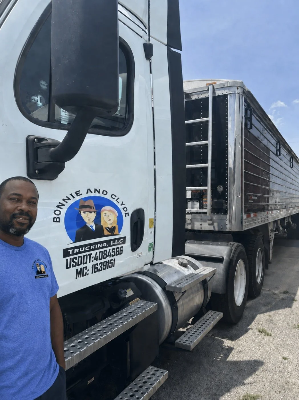 A white semi-truck with a black trailer parked on a paved road under a blue sky with some clouds. The truck has a logo for Bonnie and Clyde Trucking, LLC on the door.