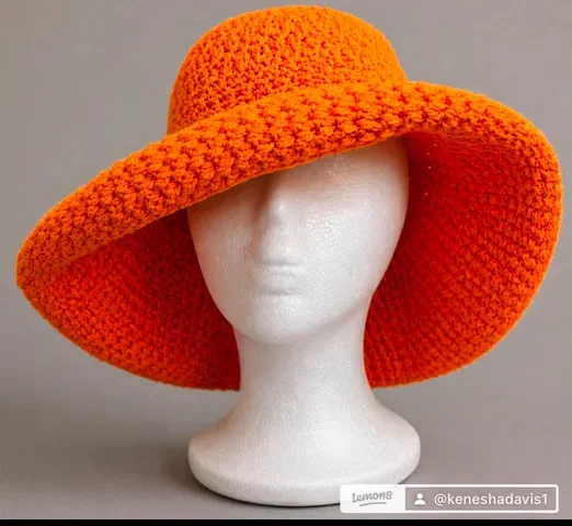 Bright orange crocheted wide‑brim hat displayed on a white mannequin head.