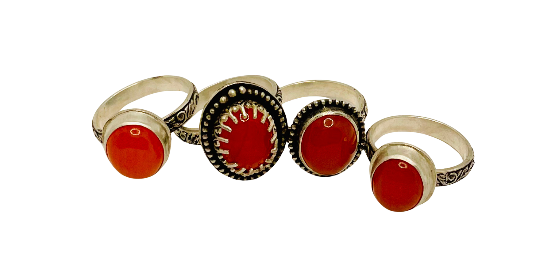 A collection of handcrafted silver rings featuring round and oval carnelian gemstones, each with unique decorative metalwork and detailed band designs.