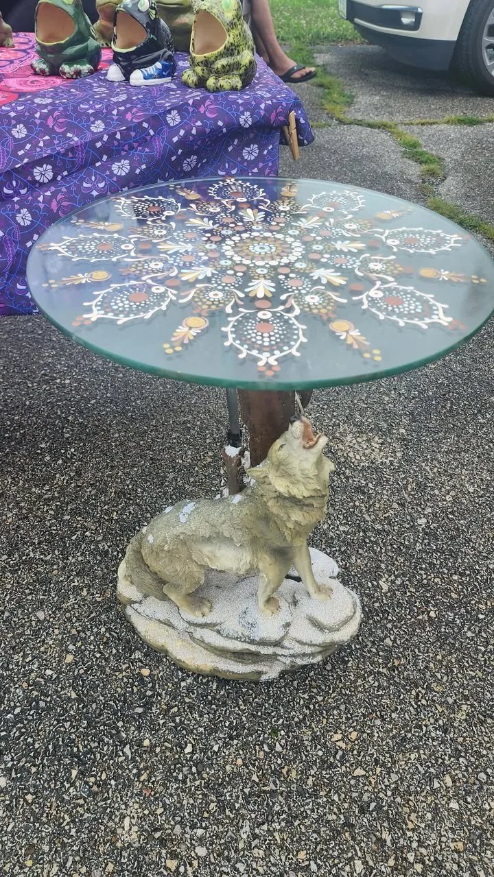 Glass‑top table with a colorful mandala design supported by a sculpted howling wolf base.