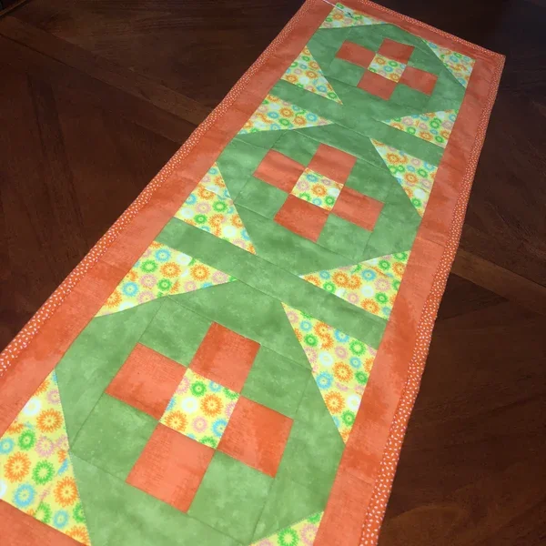 Handmade floral patchwork table runner with orange and green quilt blocks