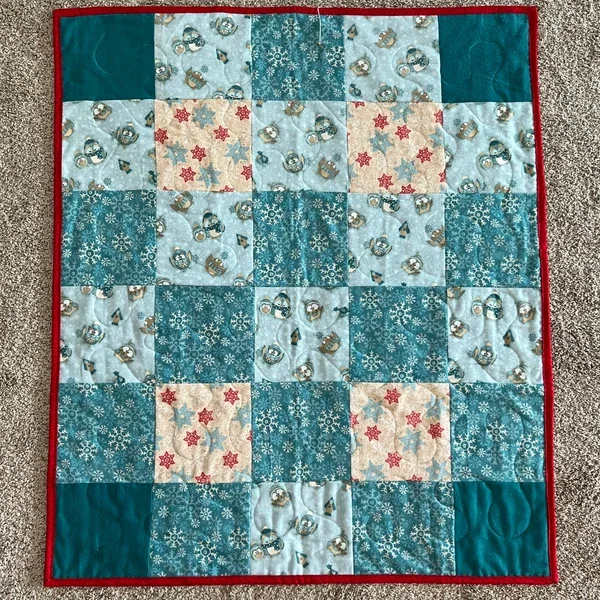 Handmade winter-themed patchwork quilt with snowflakes and holiday blocks