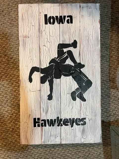 Wooden Iowa Hawkeyes wrestling sign with black silhouette design.