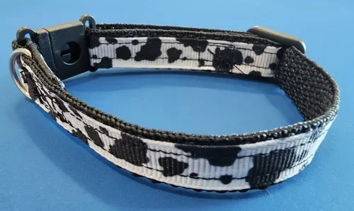 Handmade cow‑print dog collar with black buckle and metal D‑ring, created by From Ember to Ash.