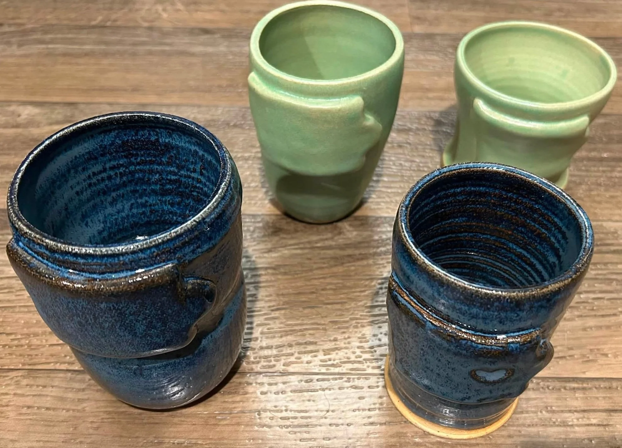 Handmade ceramic cups in blue and green glazes with hand‑formed ridges crafted by Purple Moon.